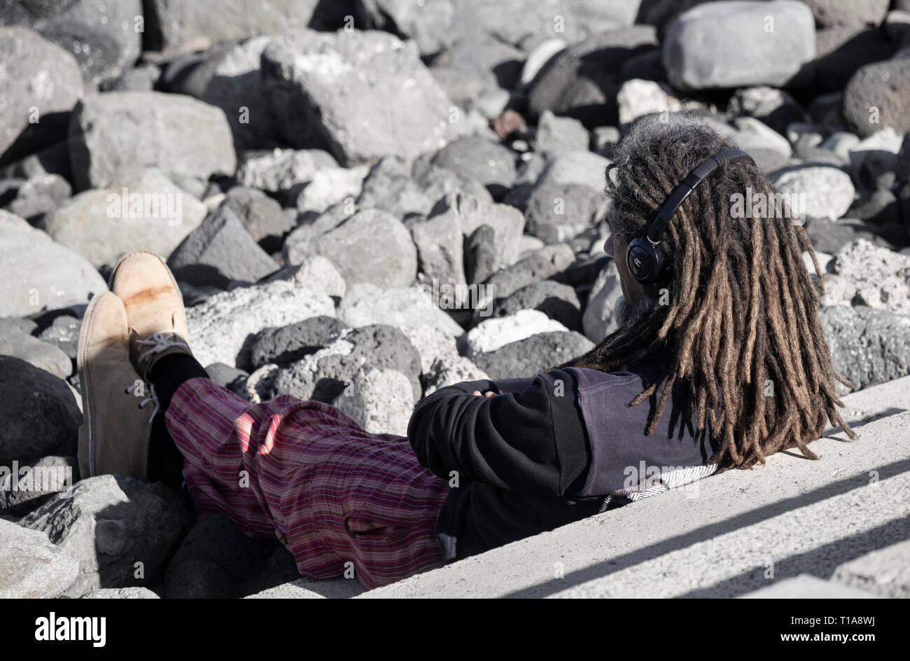 Im mittleren Alter weißer Mann mit Dreadlocks Kopfhörer tragen. Stockfoto