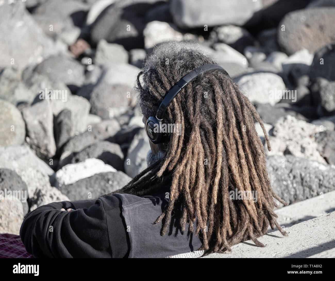 Im mittleren Alter weißer Mann mit Dreadlocks Kopfhörer tragen. Stockfoto