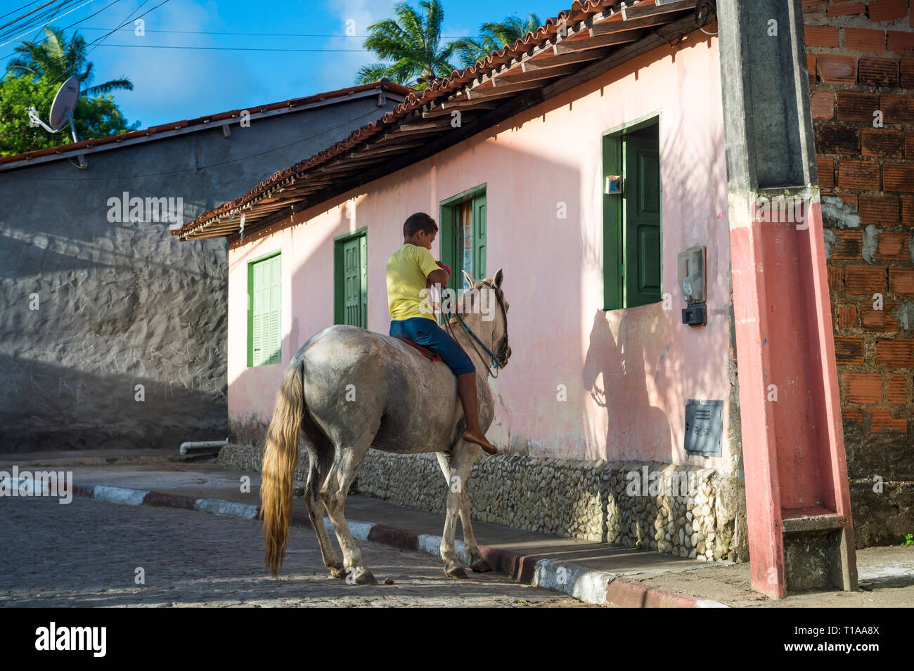 BAHIA, BRASILIEN - MÄRZ 2017: Eine junge brasilianische Junge Reiter ein Pferd dreht sich um auf einer Dorfstraße. Stockfoto