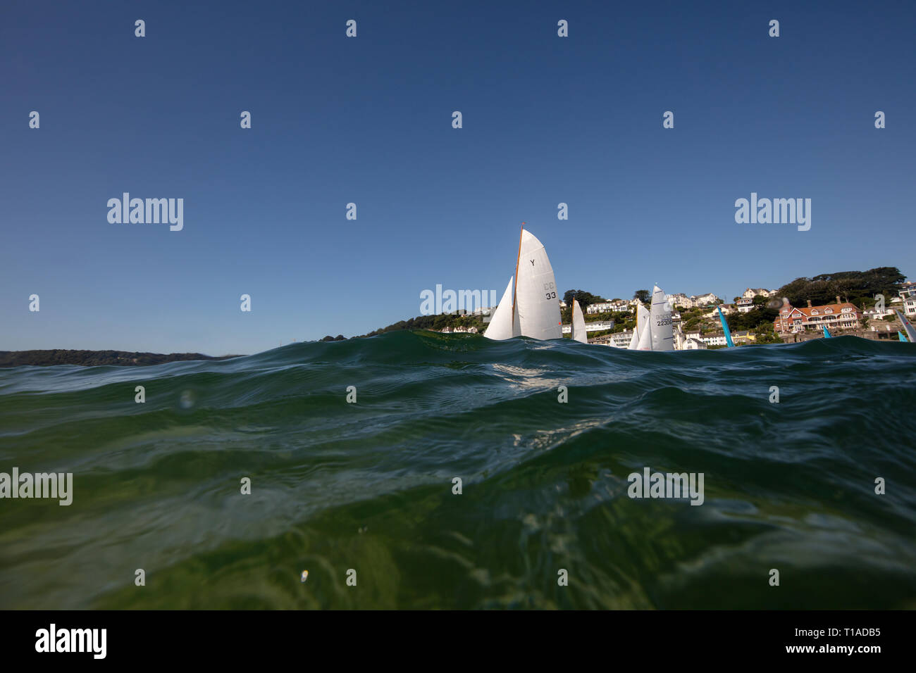 Eine Yacht segeln Vergangenheit während des Salcombe Stadt Regatta unter einem wunderschönen blauen Himmel. Stockfoto