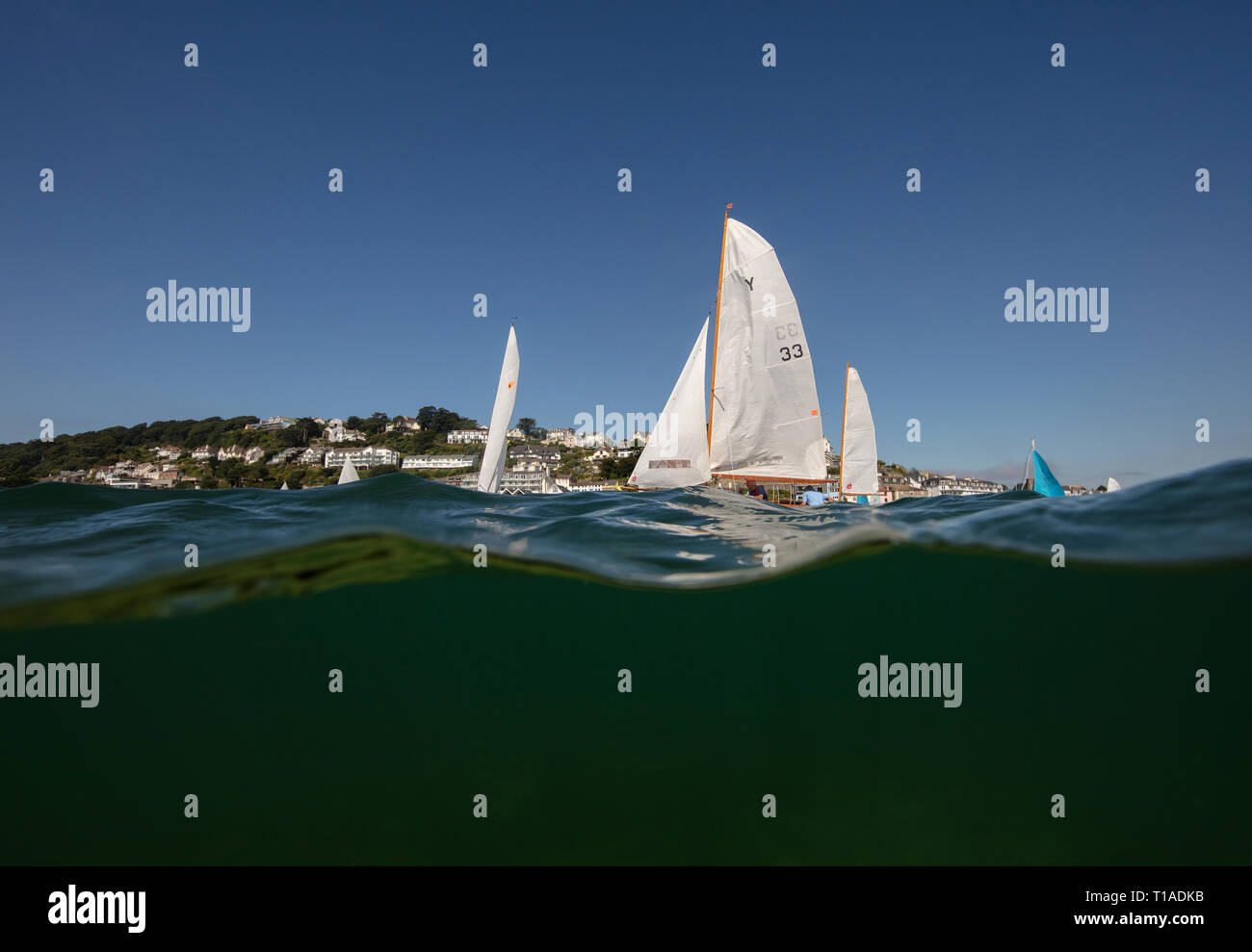 Eine Yacht segeln Vergangenheit während des Salcombe Stadt Regatta unter einem wunderschönen blauen Himmel. Stockfoto