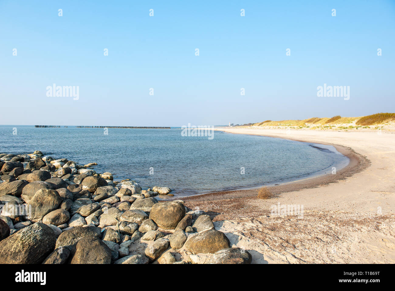 Ruhiges Meer Strand im Sommer mit großen Felsen und Holzpfähle aus alten breakewater im Meer. blue sky Stockfoto