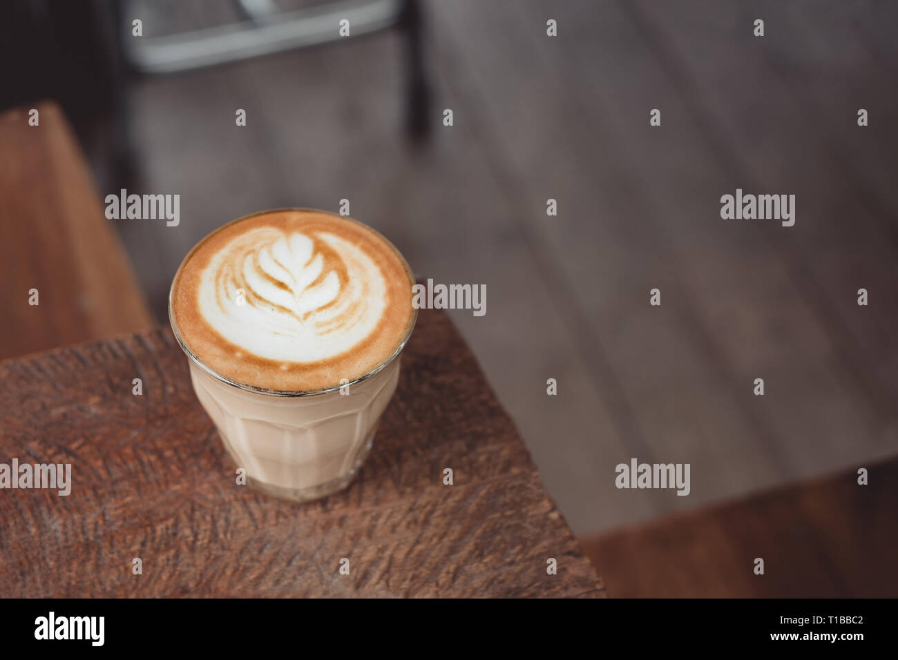 Heißen Cappuccino Tasse auf Holz- Fach mit latte Kunst auf Holz Tisch im Cafe. Essen und Trinken Konzept Stockfoto