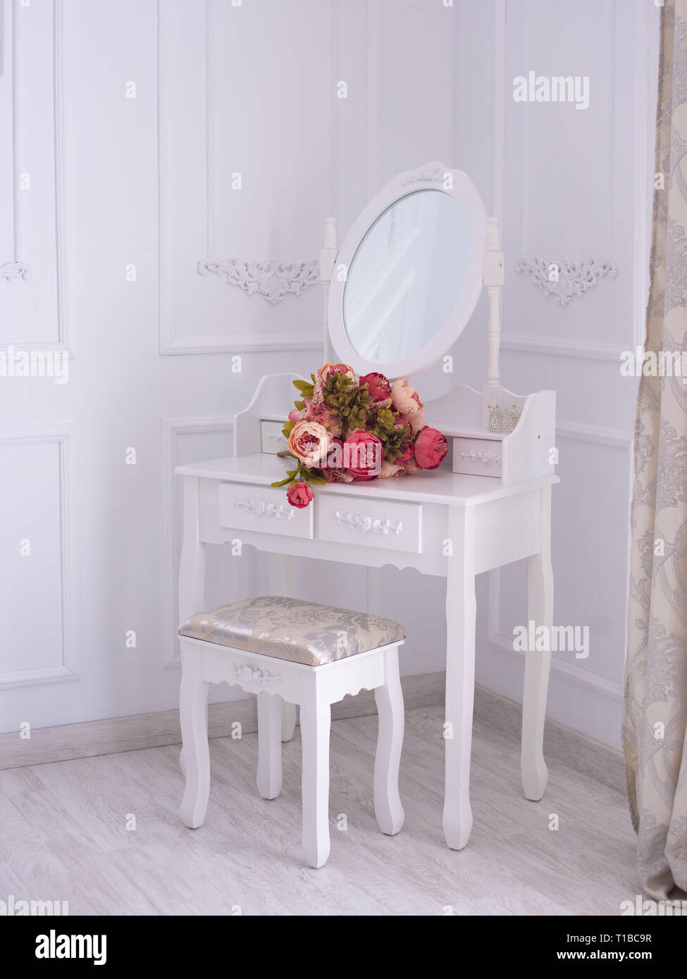 Schminktisch mit Spiegel und Blumen auf dem Zimmer Stockfoto