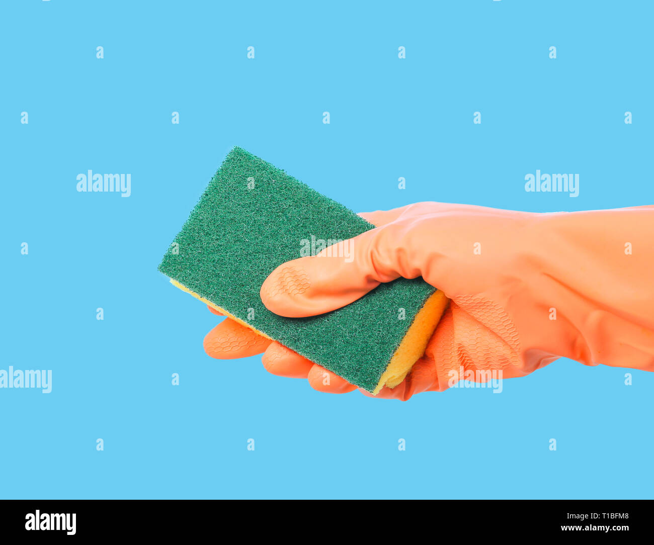Orange behandschuhte Hand Reinigung mit Schwamm auf blauem Hintergrund Stockfoto