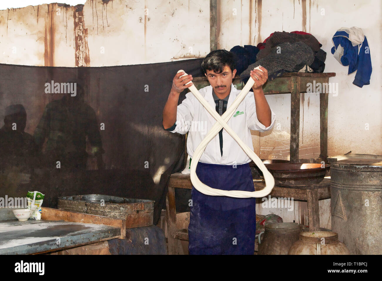 Junger uigurischer Mann, der handgezogene Nudeln herstellte, Kashgar-Sonntagsmarkt, Kashgar, Xinjiang Autonome Region, China. Stockfoto