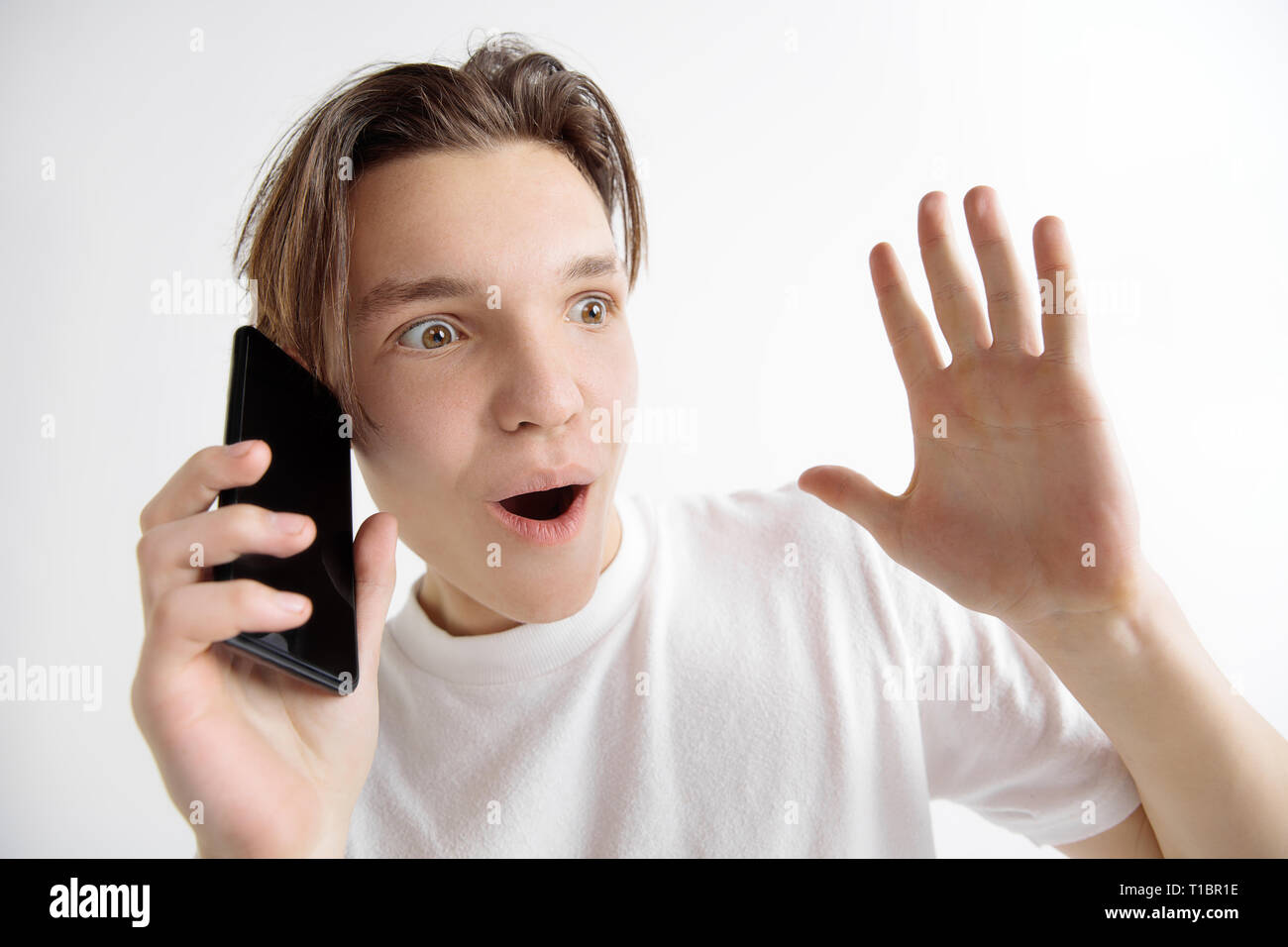 Wow. Sein unglaubliches. Schockierend und Breaking News. Junge hübsche Teenager zeigt der Bildschirm des Smartphones auf grauem Hintergrund. Menschliche Gefühle, Mimik, Werbung, Bildung Konzept. Stockfoto