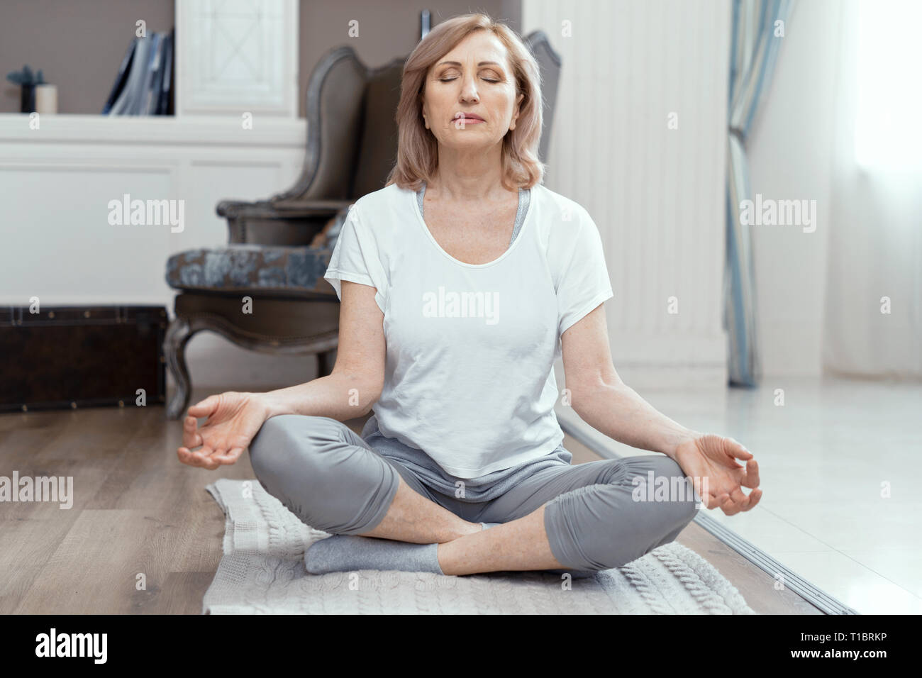 Eine Frau im Alter von über 50 Jahren ist Yoga zu Hause. Stockfoto