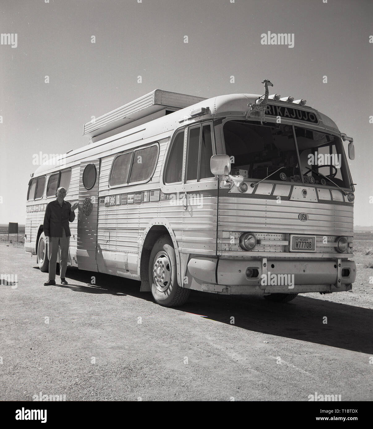 1960, Afghanistan, ein Mann, der an der Tür zu einem Amerikanischen reisen oder Reisebus, 'Rikajujo', mit einem Nevada Nummernschild oder Lizenz auf einem staubigen, Kies Straße geparkt werden. Stockfoto