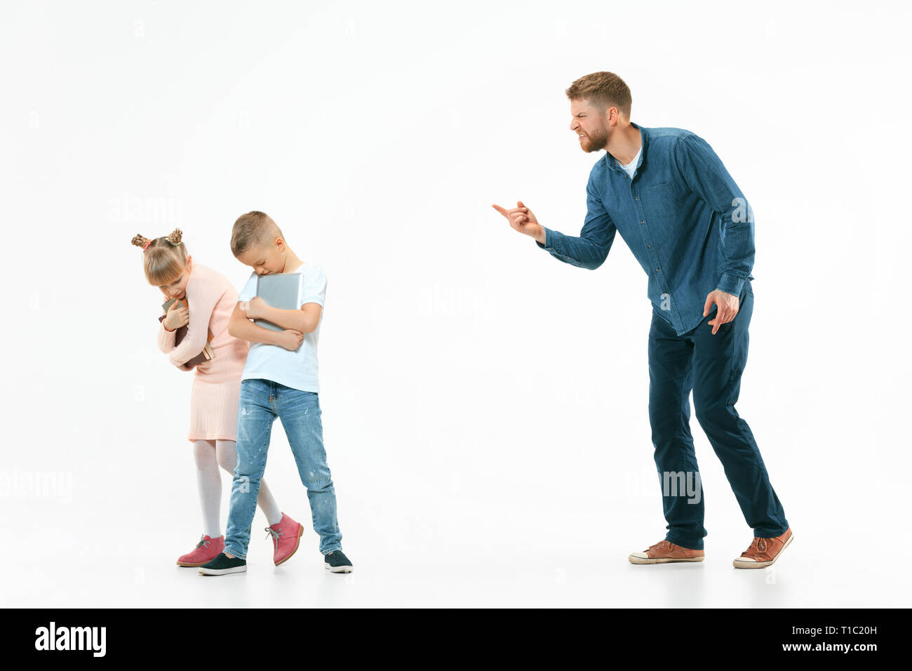 Wütende Vater seinen Sohn und Tochter zu Hause Schelte. Studio shot der emotionalen Familie. Menschliche Emotionen, Kindheit, Probleme, Konflikte, das häusliche Leben, Beziehung Konzept Stockfoto