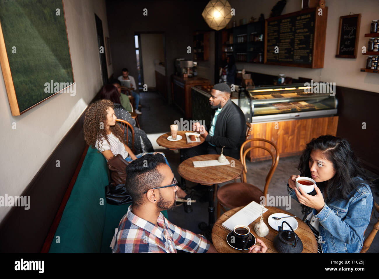 Unterschiedliche Menschen an Tischen sitzen in einem angesagten Cafes Stockfoto