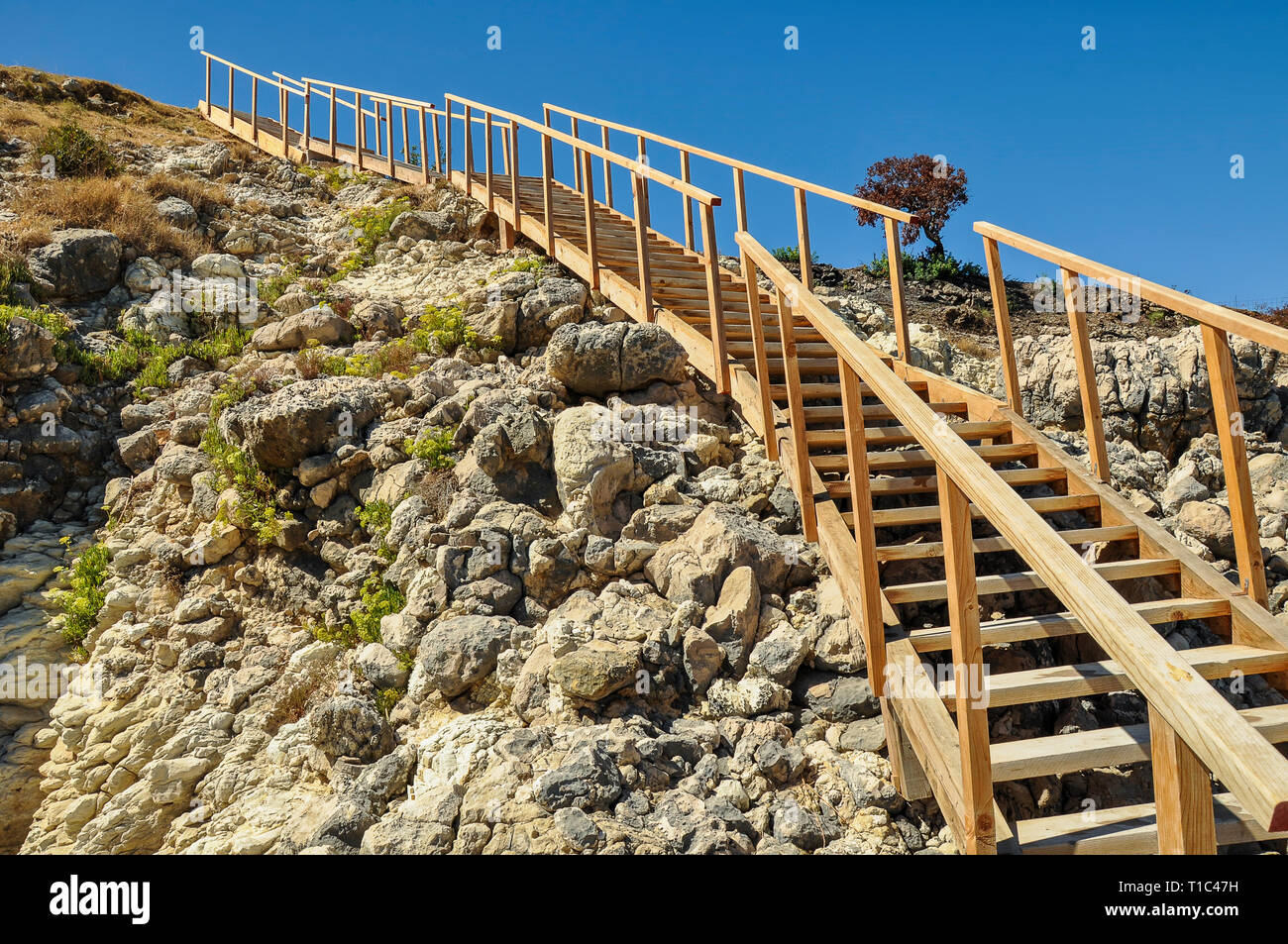 Hölzerne Treppe an der felsigen Küste entfernt. Und sonniger Sommertag im Mittelmeer statt. Treppen zum Himmel. Stockfoto