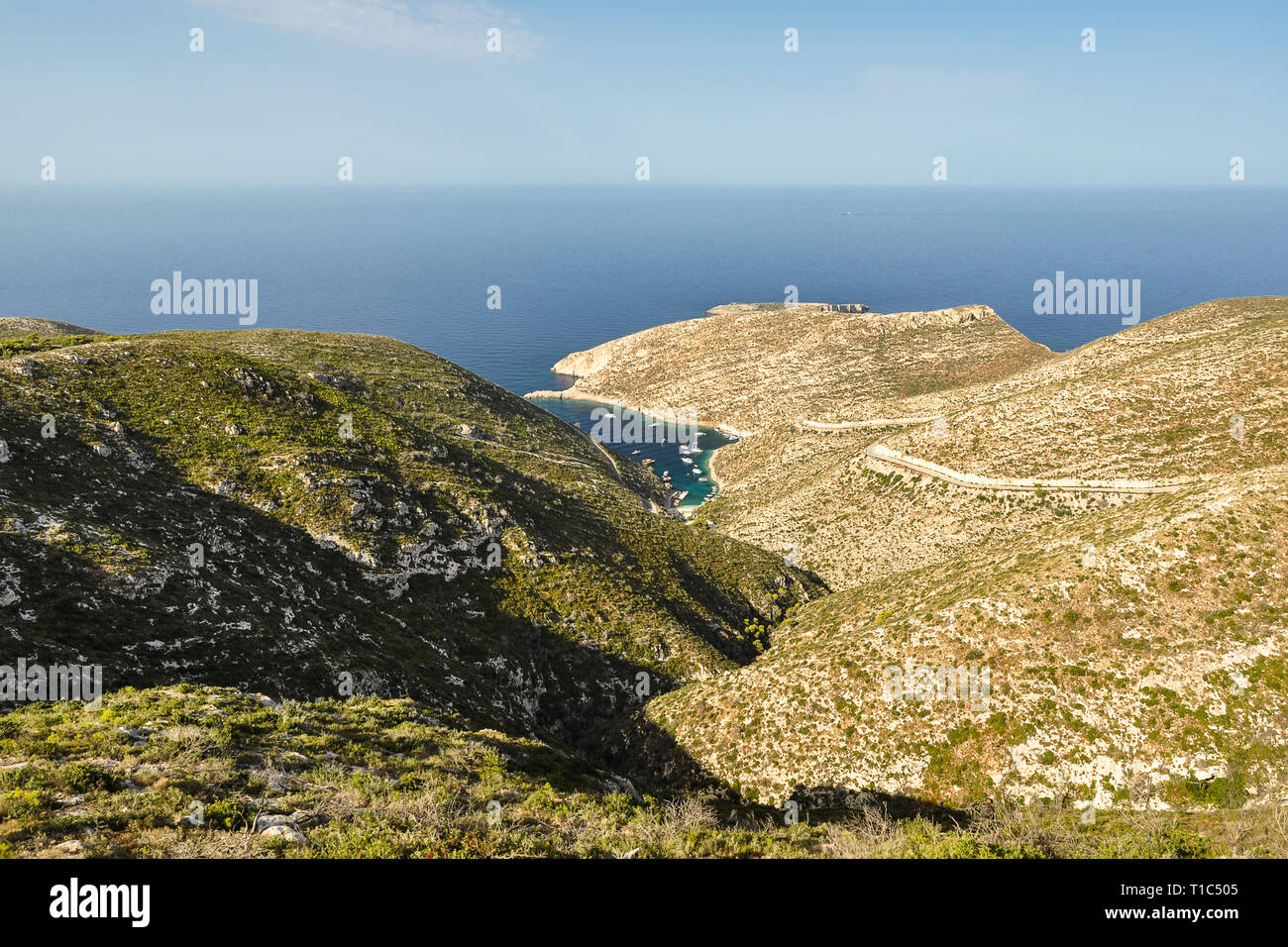 Blick von oben auf die Kleinen, Griechenland Hafen mit blauem, kristallklarem Wasser zwischen Rock Küste mit Hügeln. Sommer Marine mit Blick auf den blauen Himmel, Meer und Berg Stockfoto