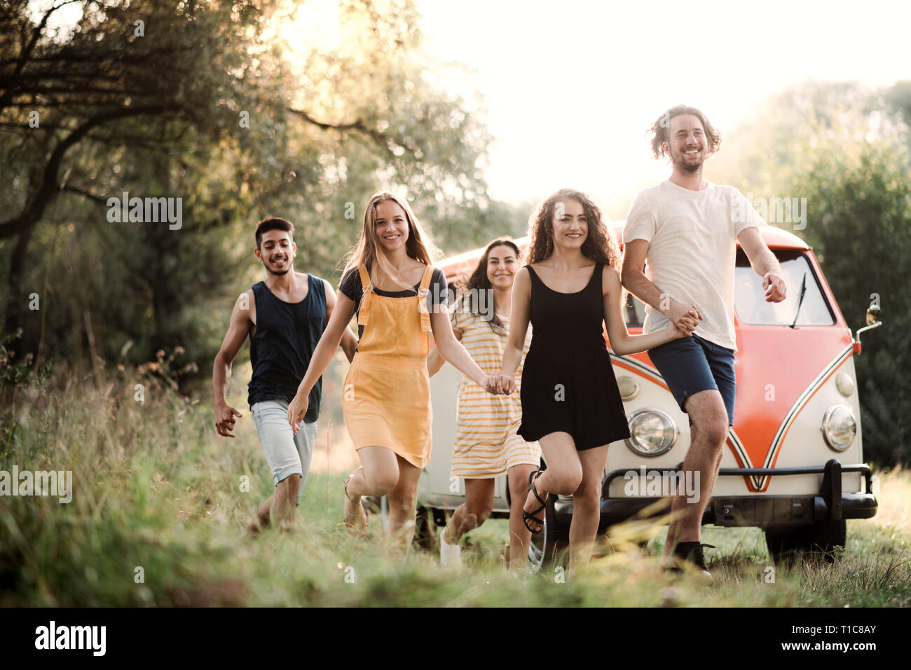 Eine Gruppe junger Freunde auf einem Roadtrip durch die Landschaft läuft. Stockfoto