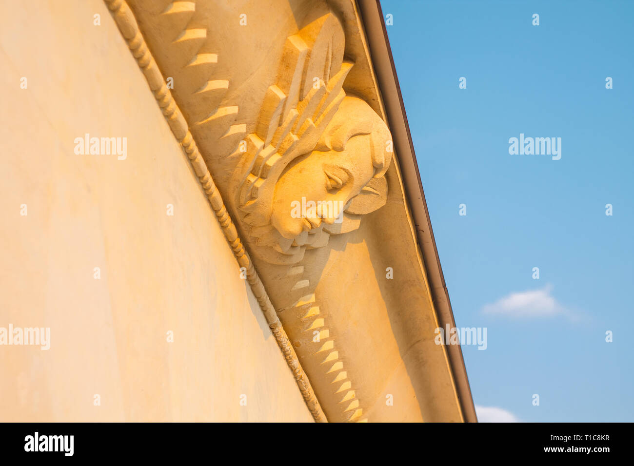 Stuck Skulptur eines weiblichen Maske mit Flügeln als dekoratives Element des Gebäudes gegen den blauen Himmel bei Sonnenuntergang Stockfoto