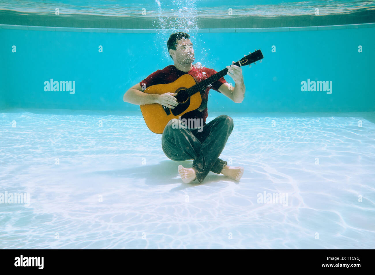 Junge Mann spielt Musik mit Gitarre und Gesang Song Unterwasser Stockfoto