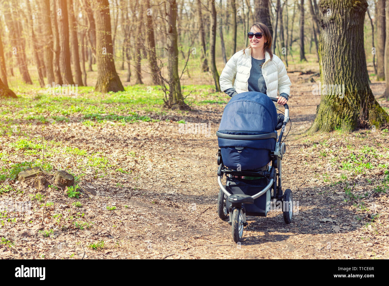 Schne junge erwachsene Frau wandern mit Baby im Kinderwagen durch den Wald  oder Park auf hellen, sonnigen Tag. Gesunder Lebensstil und Kinder  healthcare. Glcklich Stockfotografie - Alamy