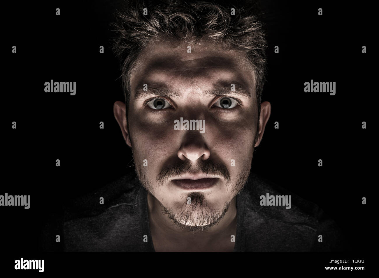 Portrait von ernsthaften jungen Mann auf schwarzem Hintergrund Stockfoto