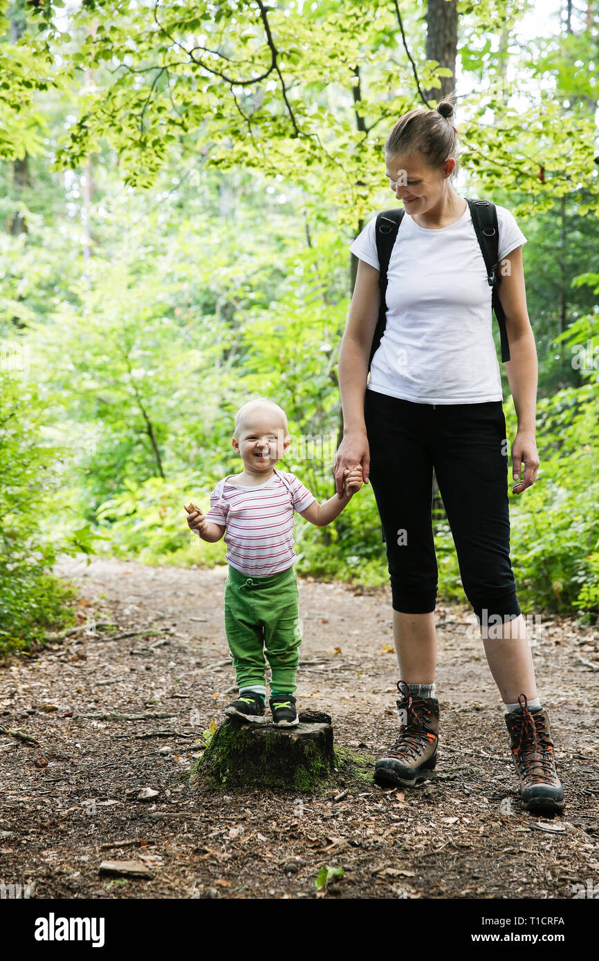 Mutter Hand in Hand mit ihrem Sohn gewidmet, zu Fuß in den Wald. Familie, aktiver Lebensstil, Mutter - Sohn Beziehung Konzept. Stockfoto