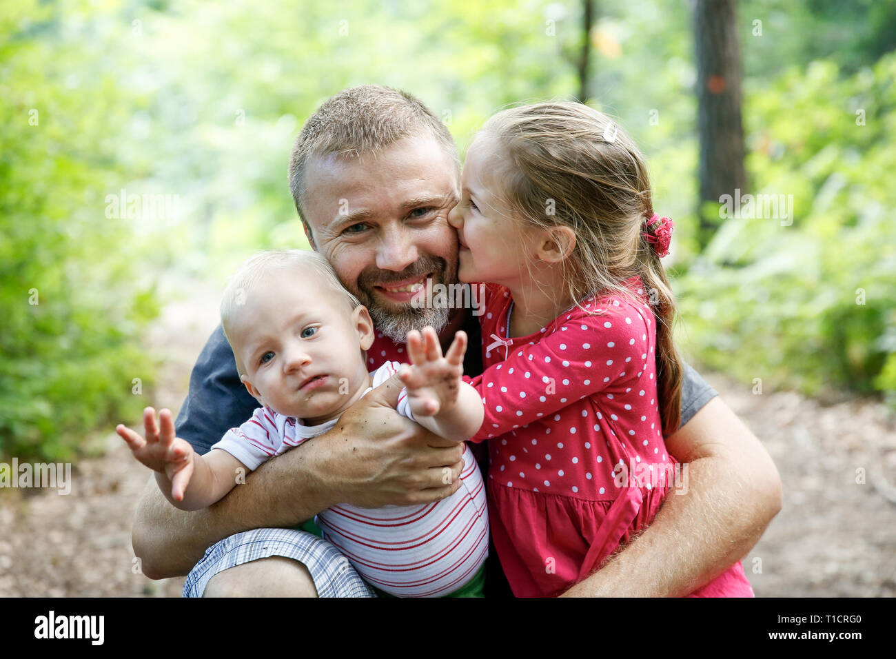 Vater seinen Sohn und Tochter umarmen gewidmet, genießen die outdoor. Familie Liebe und Bindung, aktiven Lebensstil, Vatertag Konzept. Stockfoto