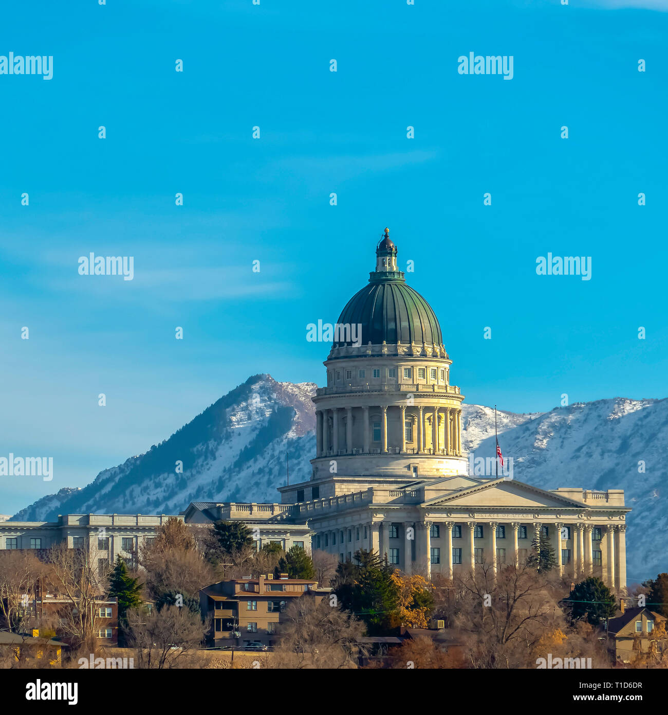 Utah State Capital Building gegen die schneebedeckten Berge. Utah State Capital Building eindrucksvoll inmitten von Gebäuden und Bäumen in Salt Lake City mit einem sn Stockfoto