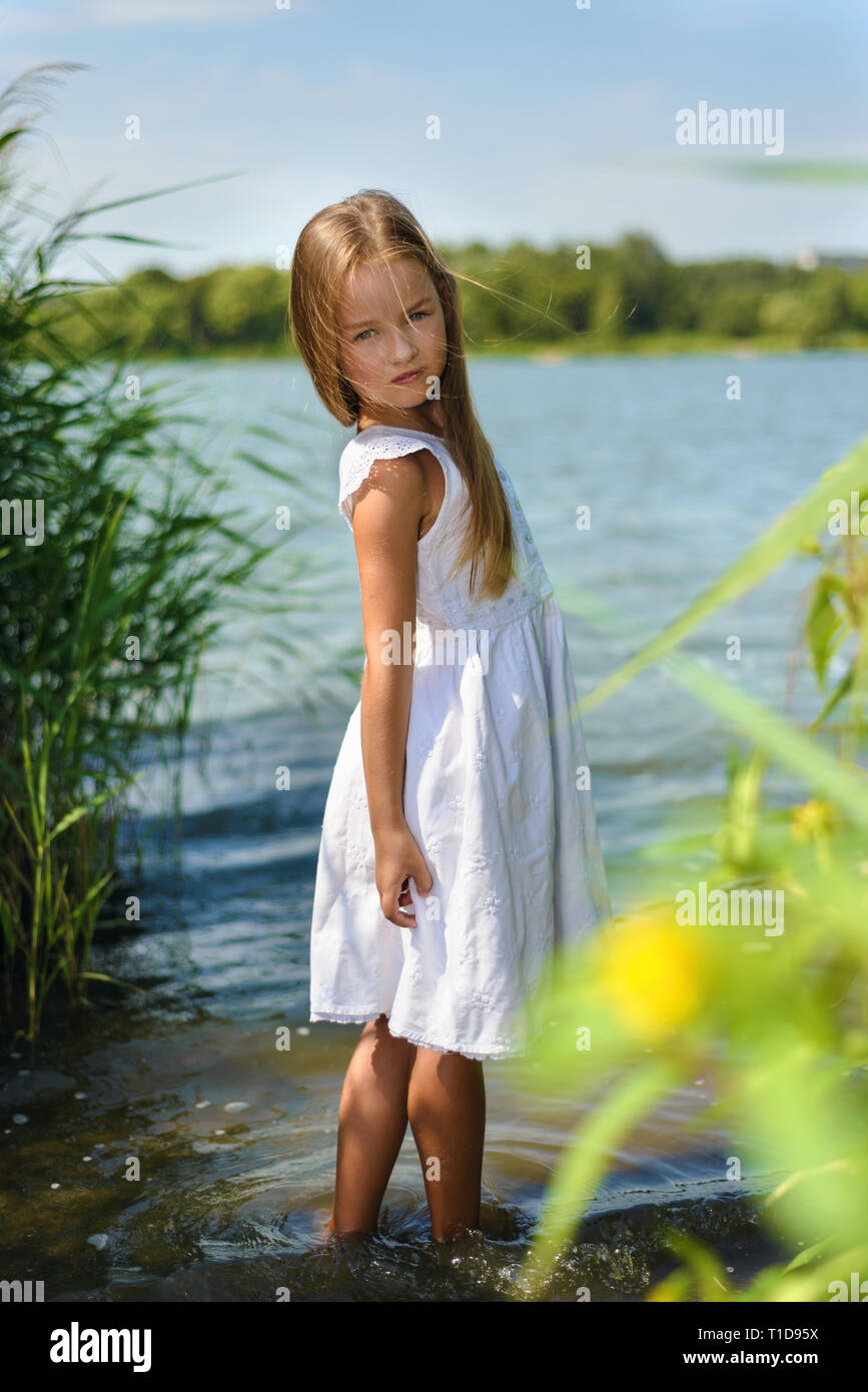 Süße kleine Mädchen in weißem Kleid im Wasser im Fluss Stockfoto