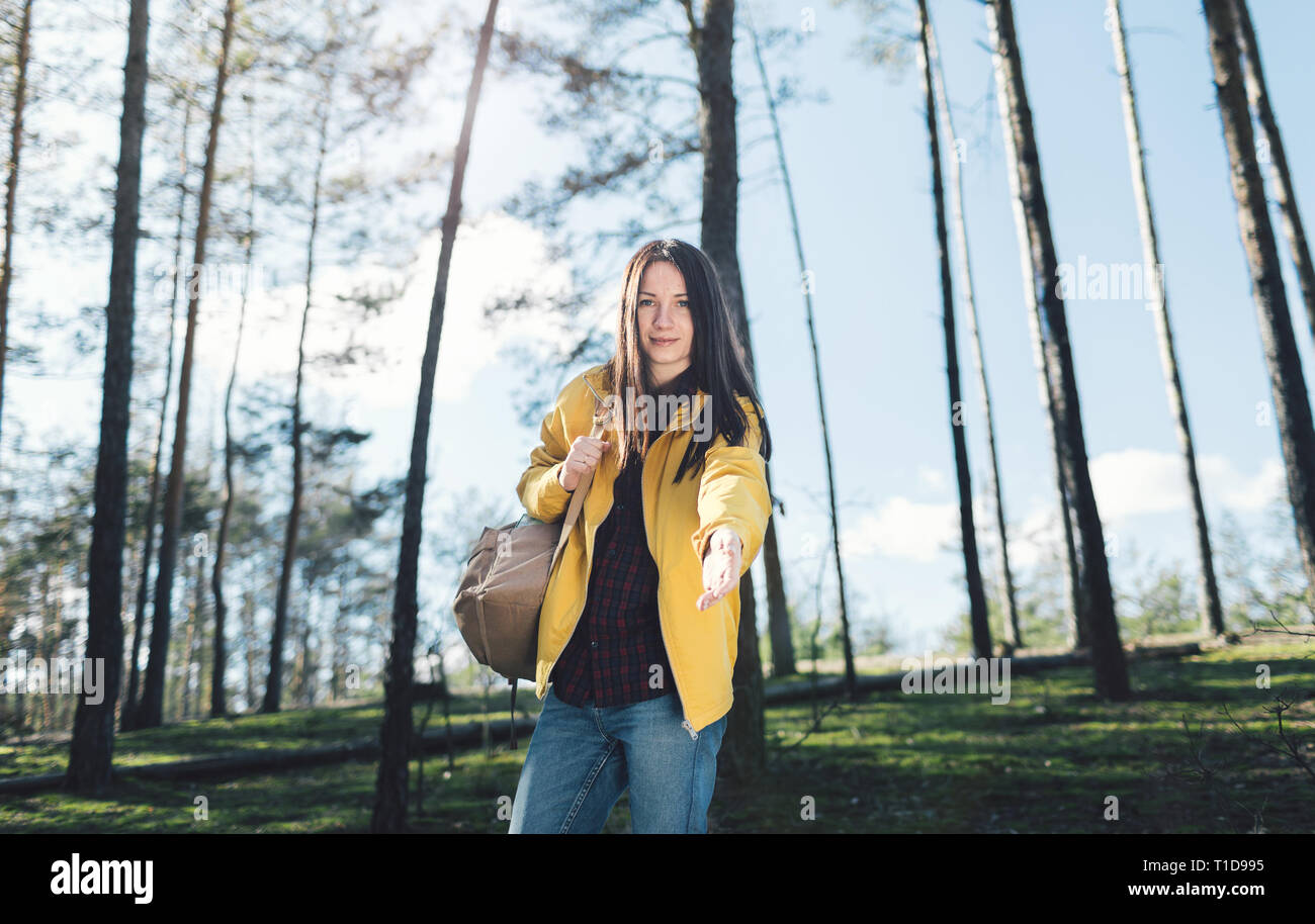 Junge Frau in das Holz mit einem Rucksack gibt eine Hand schauen direkt in die Kamera Stockfoto