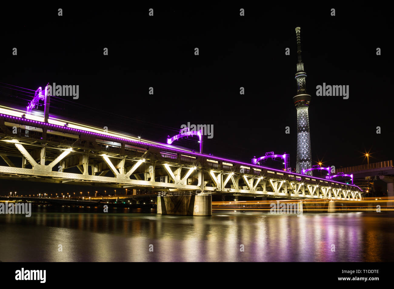 Die tobu Bahnlinie auf dem Sumida River in Downtown Tokyo ausgeführt wird beleuchtet in leuchtenden Violett leuchtet. Die Skytree leuchtet auch und eine lange Stockfoto