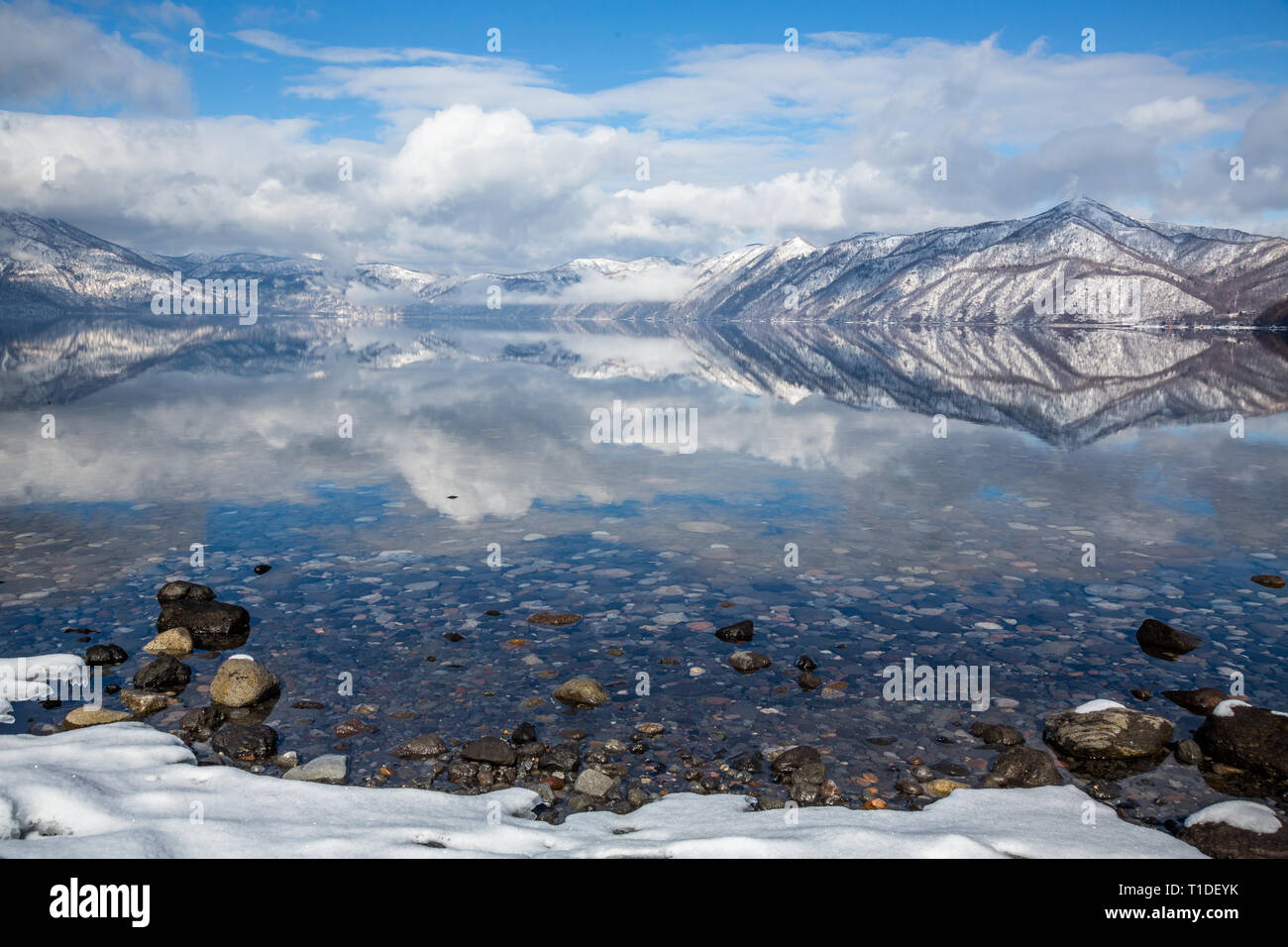 Felsigen Strand Küste der Ruhe See auf der Insel Hokkaido in Japan. Wasser reflektiert die Berge und Wolken rund um Lake Shikotsu in der Nähe von Sapporo Stockfoto