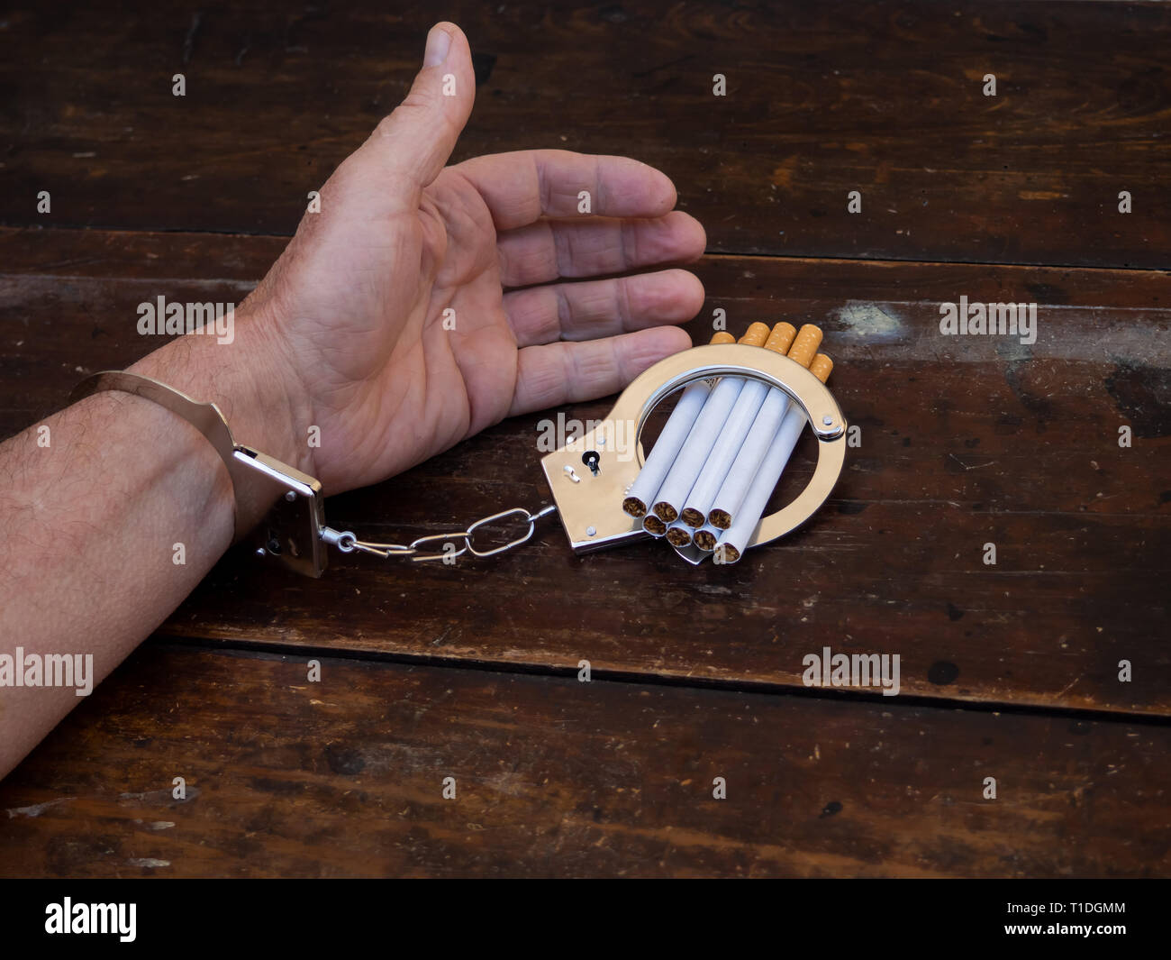 Ein Mann in Handschellen zu einer Handvoll von Zigaretten. Nikotinsucht Konzept Stockfoto
