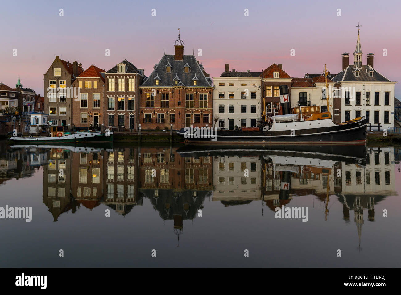 Maassluis, Niederlande - 26. Februar 2019: Der Hafen von Maassluis mit alten Boote, Schlepper und monumentale Häuser auf einem eveniung mit Sonnenuntergang. Stockfoto