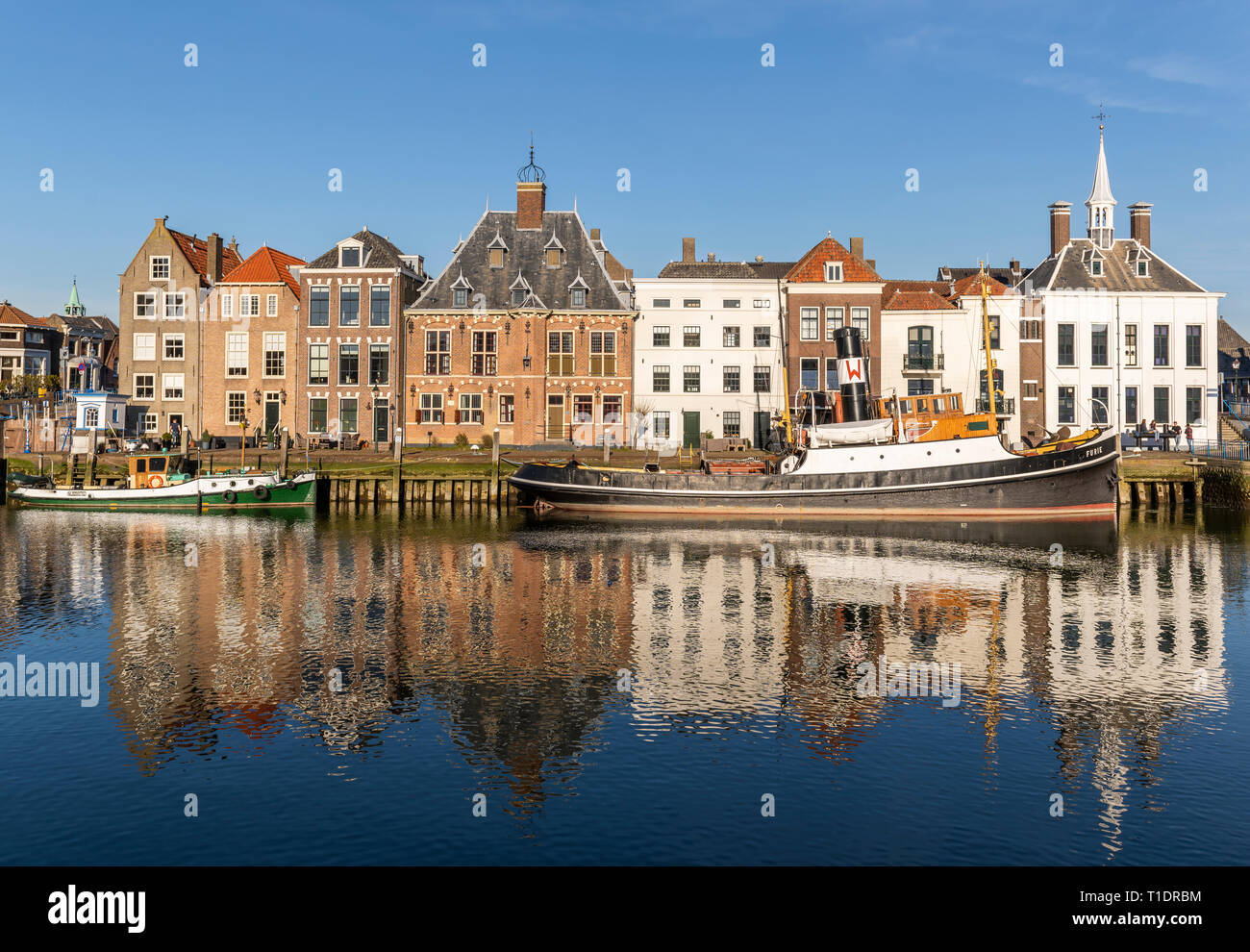 Maassluis, Niederlande - 26. Februar 2019: Der Hafen von Maassluis mit alten Boote, Schlepper und monumentale Häuser an einem sonnigen Tag. Stockfoto