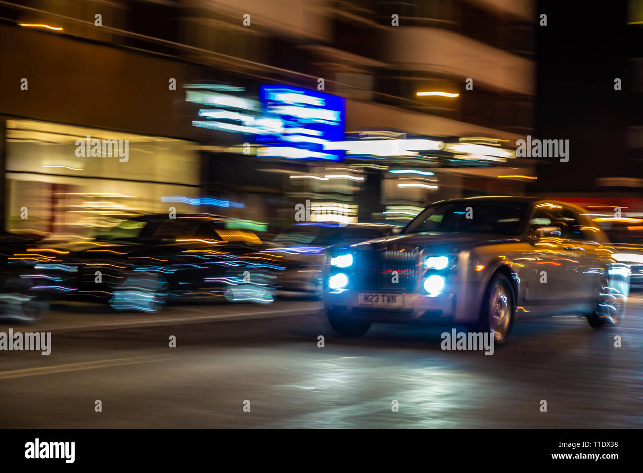 Verschwommenes Bild von sich schnell bewegenden Rolls-Royce Phantom Limousine auf einer Londoner Straße bei Nacht Stockfoto