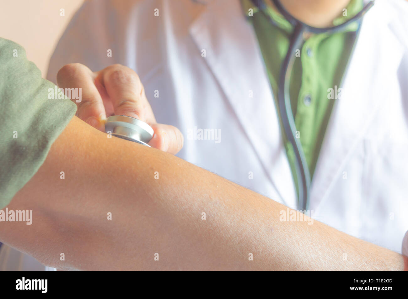 Ein Arzt Kontrolle der Blutdruck und Puls eines Patienten mit seinem Stethoskop Stockfoto