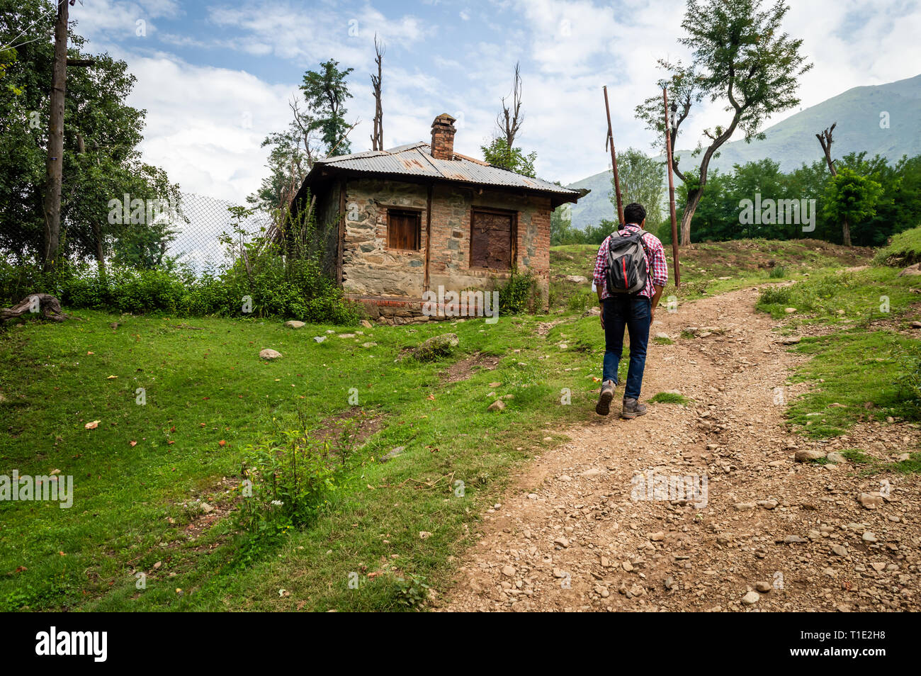 Eine Person zu Fuß auf den Hügel zu seinem Haus auf einem Feldweg in einem Dorf in Kaschmir Stockfoto