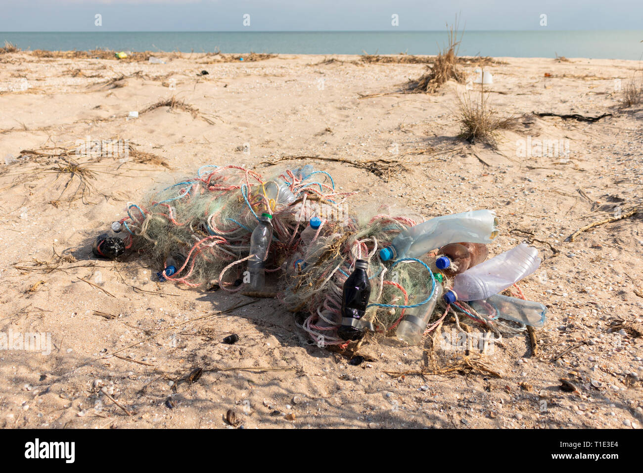 Leere Plastikflaschen und Fischernetze auf dem Sand. Müll am Strand. Dreckiges Meeresufer. Umweltverschmutzung. Rettet den Planeten. Ökologisches Problem. Stockfoto