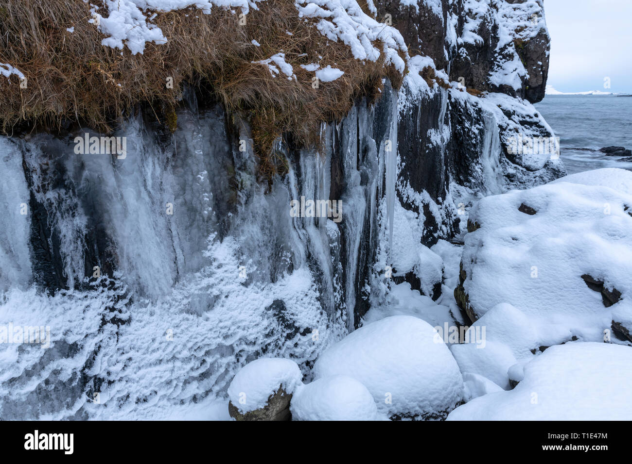 Eiszapfen und Felsen im Schnee am Meer im südlichen Island Stockfoto