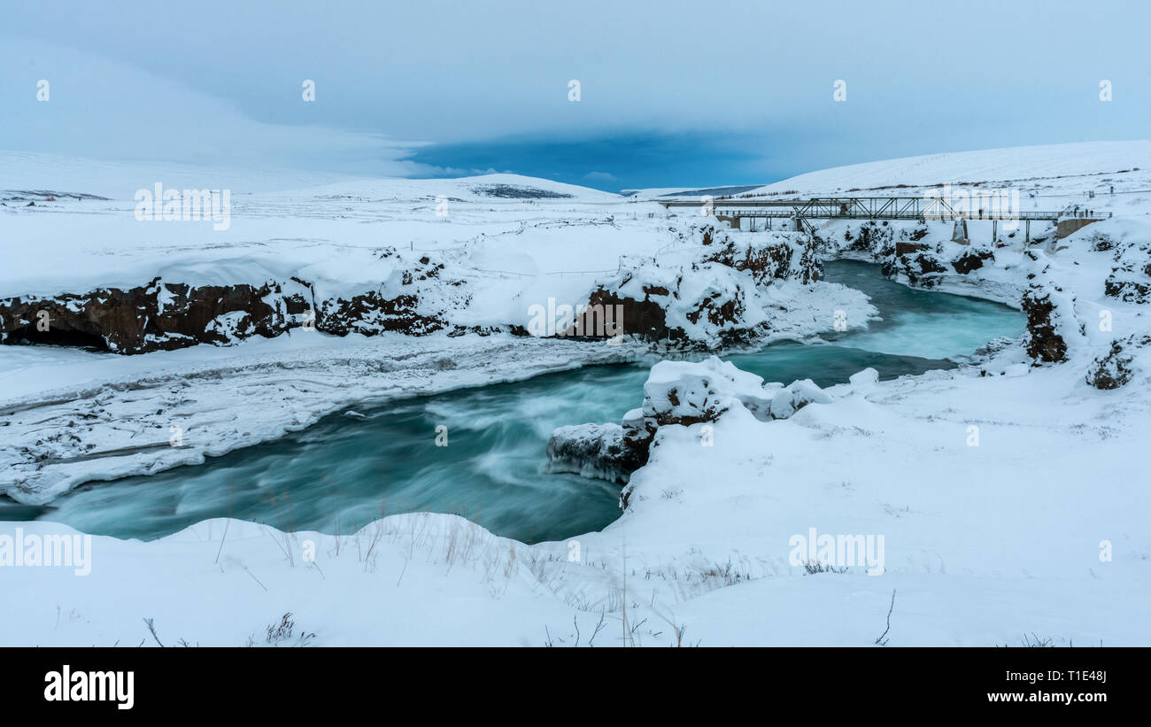 Türkisfarbene Fluss und Brücke im Schnee, Island Stockfoto