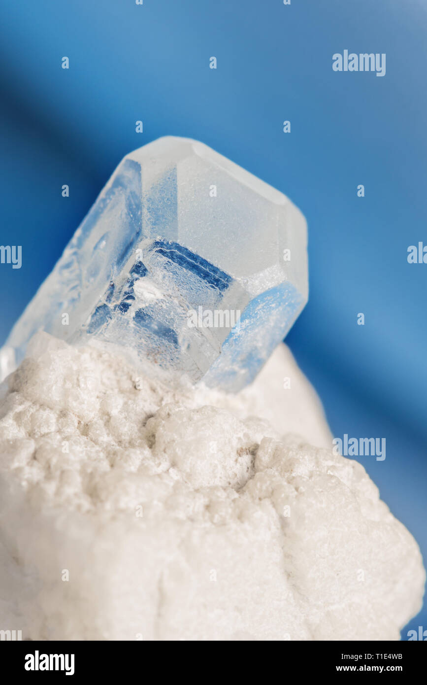 Blau aquamarin Edelstein in einem weißen Albit Matrix auf einem blauen Hintergrund Stockfoto
