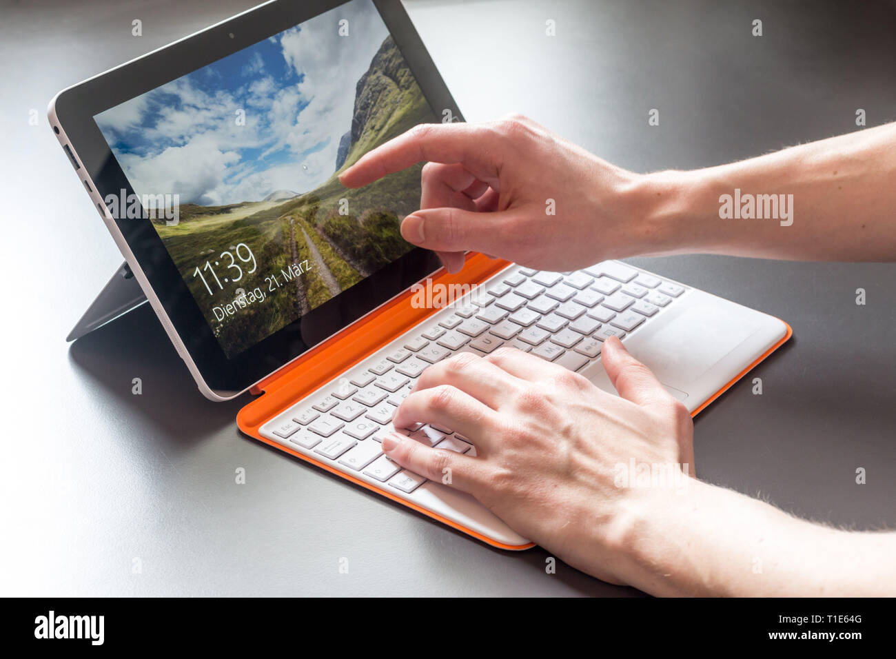 Männliche Hände und weiß orange Convertible Notebook Stockfoto