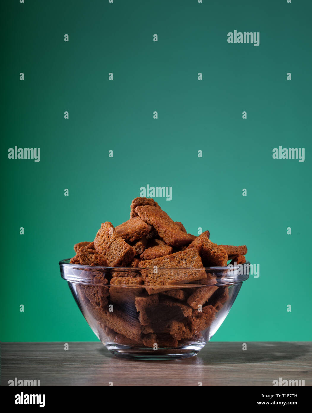 Roggen Cracker mit Gewürzen und Salz in transparente Platte auf grünem Hintergrund Stockfoto