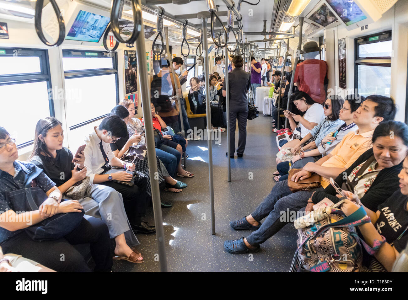 Passenegers über ihre mobilen Geräte, während Sie von Stadt U-Bahn in Bangkok, Thailand pendeln Stockfoto