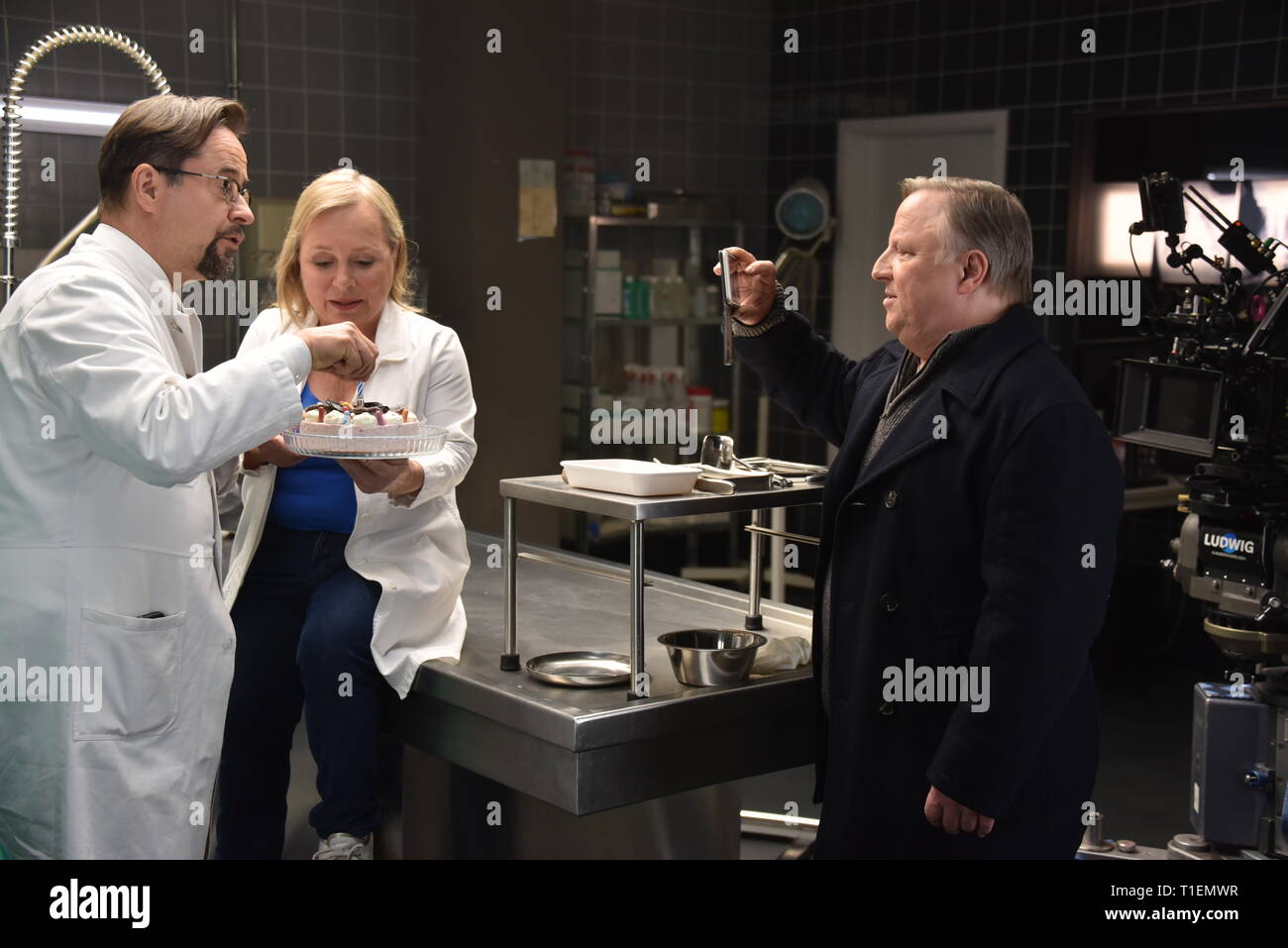 26. März 2019, Nordrhein-Westfalen, Köln: Die Schauspieler Jan Josef Liefers (L-R), Axel Prahl und Christine Urspruch stand in der Landschaft der gerichtlichen Medizin beim Fototermin am "Tatort Münster - Lakritz" (AT). Der Kuchen empfangen rühmen sich anlässlich seines Geburtstages. Foto: Horst Galuschka/dpa Stockfoto