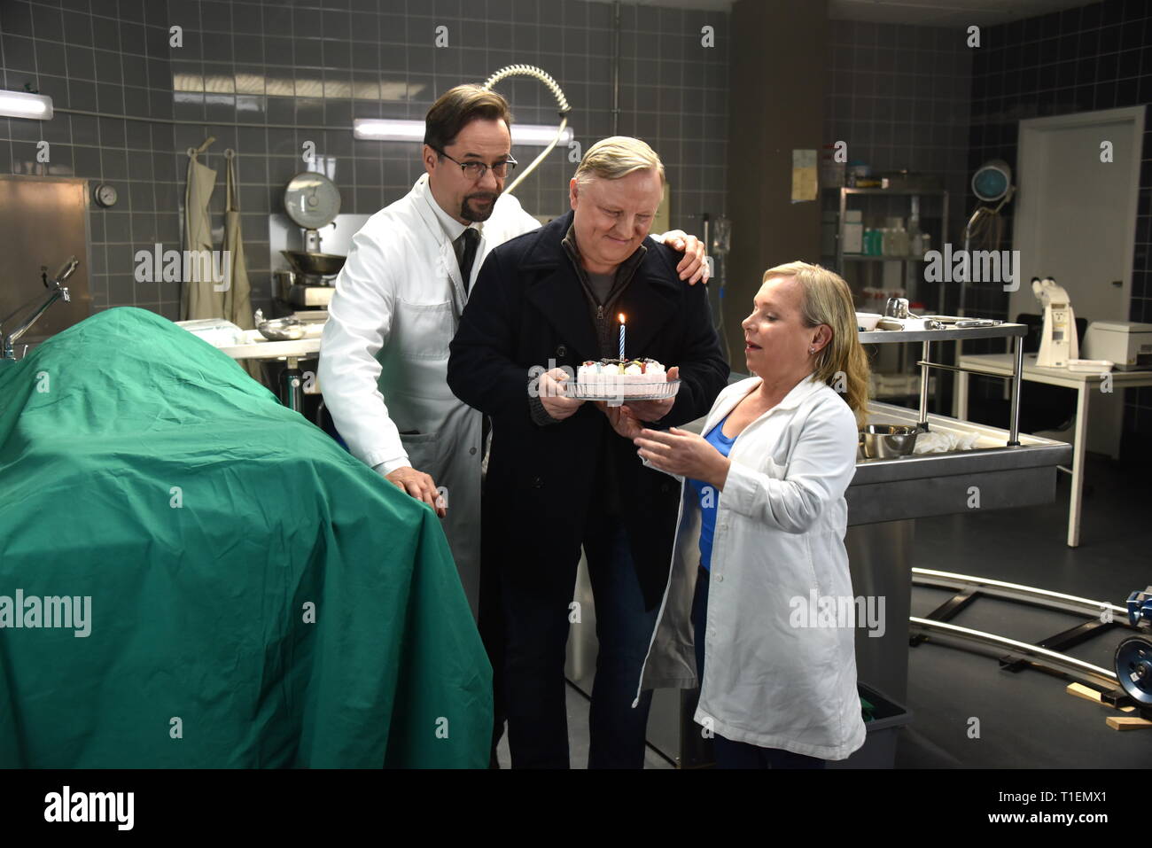 26. März 2019, Nordrhein-Westfalen, Köln: Die Schauspieler Jan Josef Liefers (L-R), Axel Prahl und Christine Urspruch stand in der Landschaft der gerichtlichen Medizin beim Fototermin am "Tatort Münster - Lakritz" (AT). Der Kuchen empfangen rühmen sich anlässlich seines Geburtstages. Foto: Horst Galuschka/dpa Stockfoto