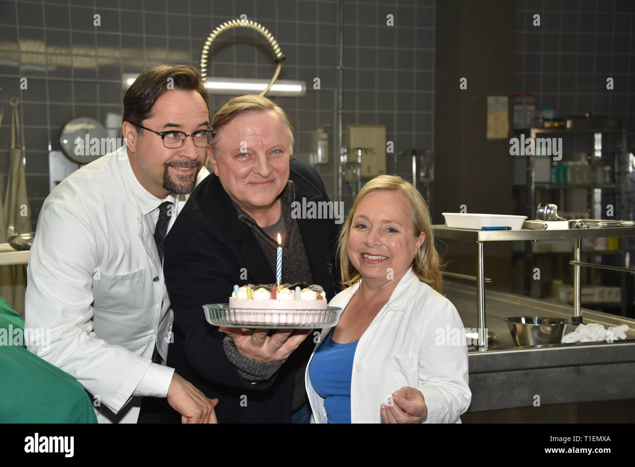 26. März 2019, Nordrhein-Westfalen, Köln: Die Schauspieler Jan Josef Liefers (L-R), Axel Prahl und Christine Urspruch stand in der Landschaft der gerichtlichen Medizin beim Fototermin am "Tatort Münster - Lakritz" (AT). Der Kuchen empfangen rühmen sich anlässlich seines Geburtstages. Foto: Horst Galuschka/dpa Stockfoto