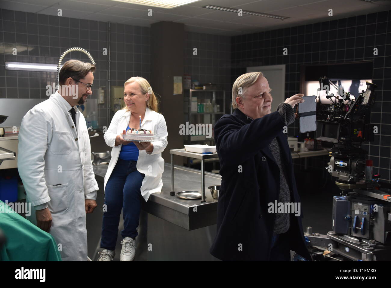 26. März 2019, Nordrhein-Westfalen, Köln: Die Schauspieler Jan Josef Liefers (L-R), Axel Prahl und Christine Urspruch stand in der Landschaft der gerichtlichen Medizin beim Fototermin am "Tatort Münster - Lakritz" (AT). Der Kuchen empfangen rühmen sich anlässlich seines Geburtstages. Foto: Horst Galuschka/dpa Stockfoto