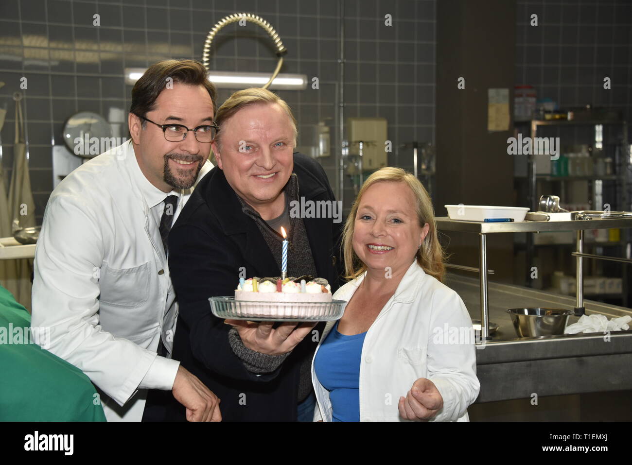 26. März 2019, Nordrhein-Westfalen, Köln: Die Schauspieler Jan Josef Liefers (L-R), Axel Prahl und Christine Urspruch stand in der Landschaft der gerichtlichen Medizin beim Fototermin am "Tatort Münster - Lakritz" (AT). Der Kuchen empfangen rühmen sich anlässlich seines Geburtstages. Foto: Horst Galuschka/dpa Stockfoto