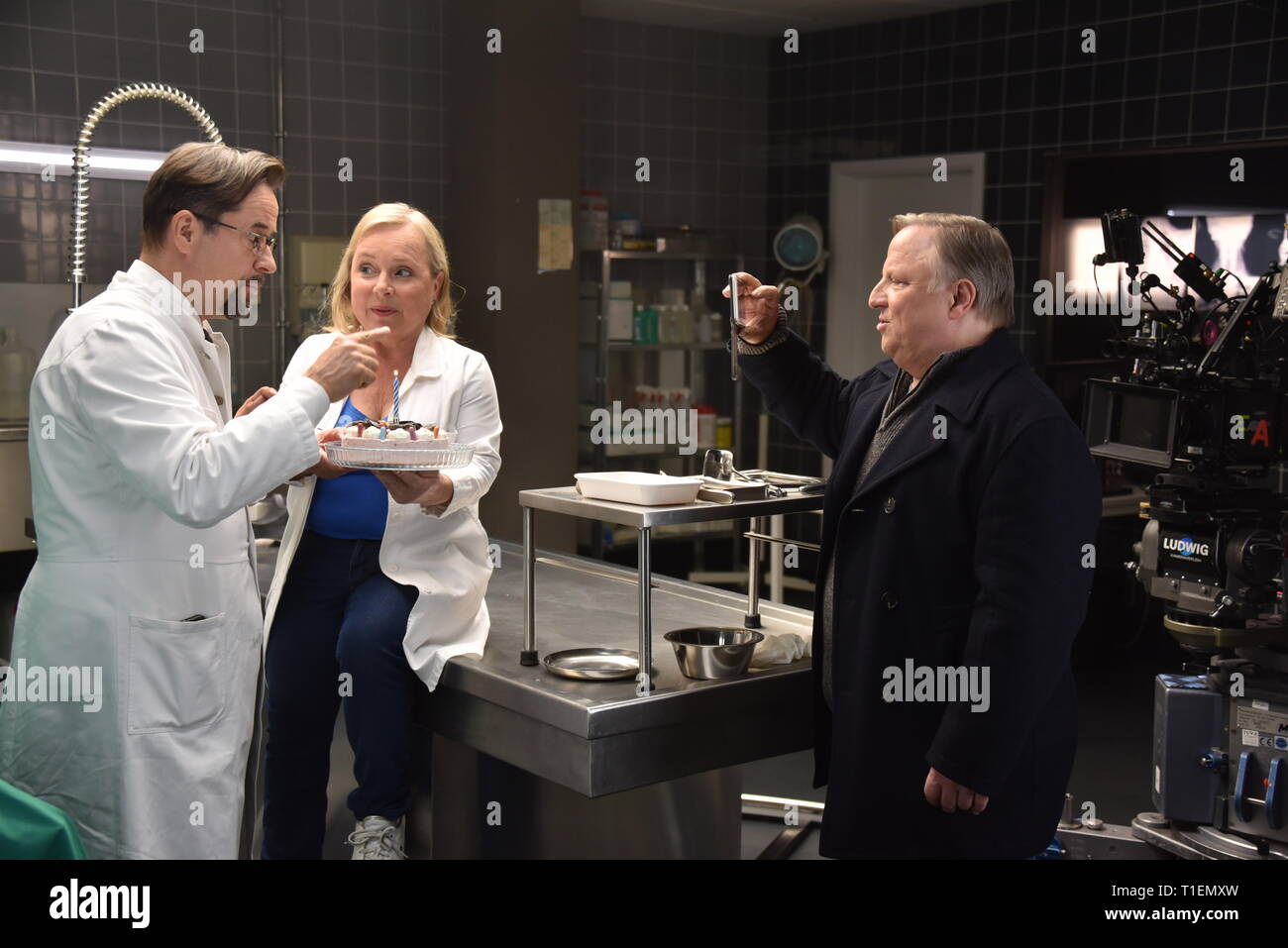 26. März 2019, Nordrhein-Westfalen, Köln: Die Schauspieler Jan Josef Liefers (L-R), Axel Prahl und Christine Urspruch stand in der Landschaft der gerichtlichen Medizin beim Fototermin am "Tatort Münster - Lakritz" (AT). Der Kuchen empfangen rühmen sich anlässlich seines Geburtstages. Foto: Horst Galuschka/dpa Stockfoto