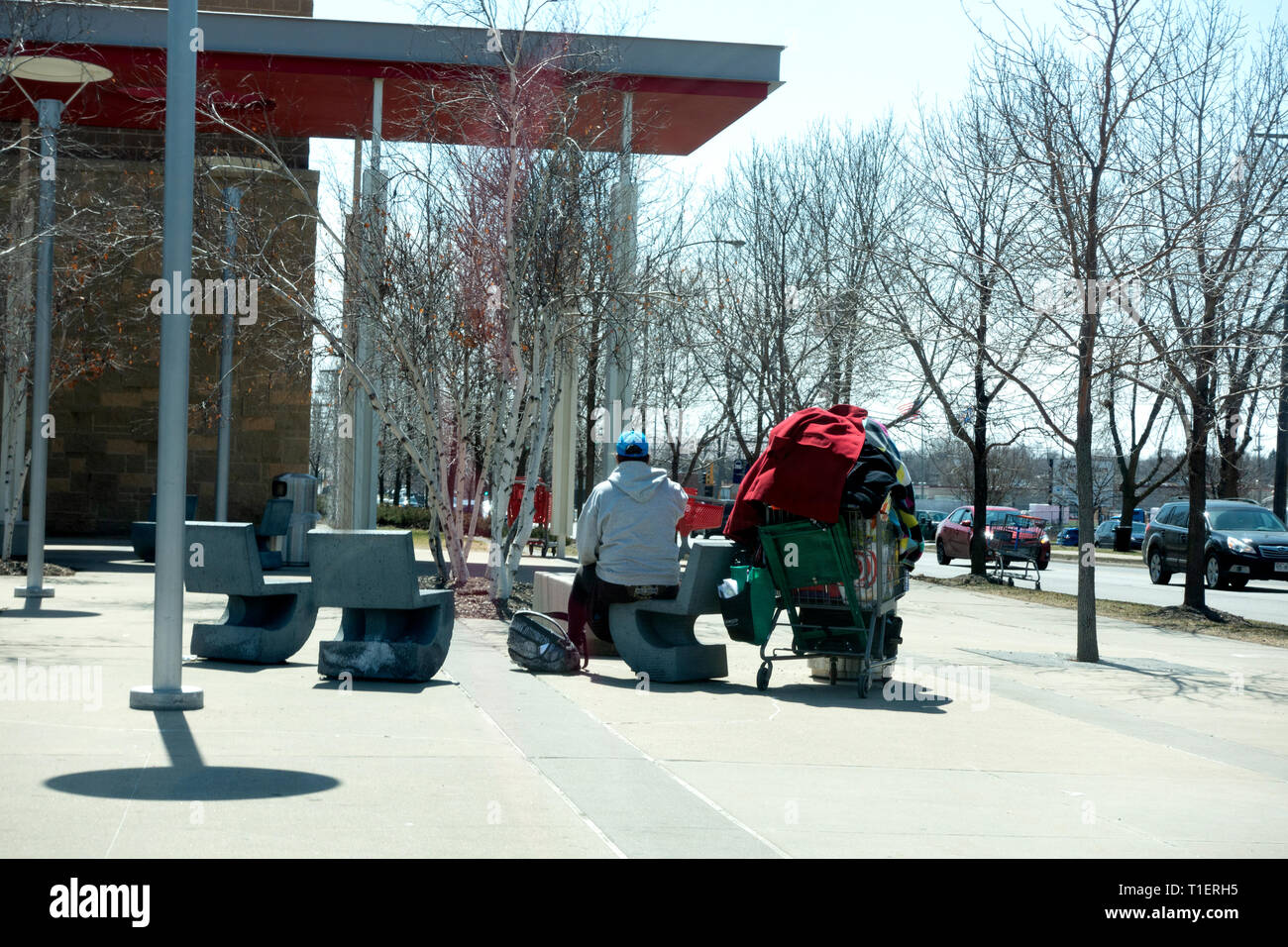 Obdachlosen Mann sitzt auf der Terrasse des Ziels mit einem Korb hoch aufgetürmt, wahrscheinlich mit all seinen Besitz. St. Paul Minnesota MN USA Stockfoto