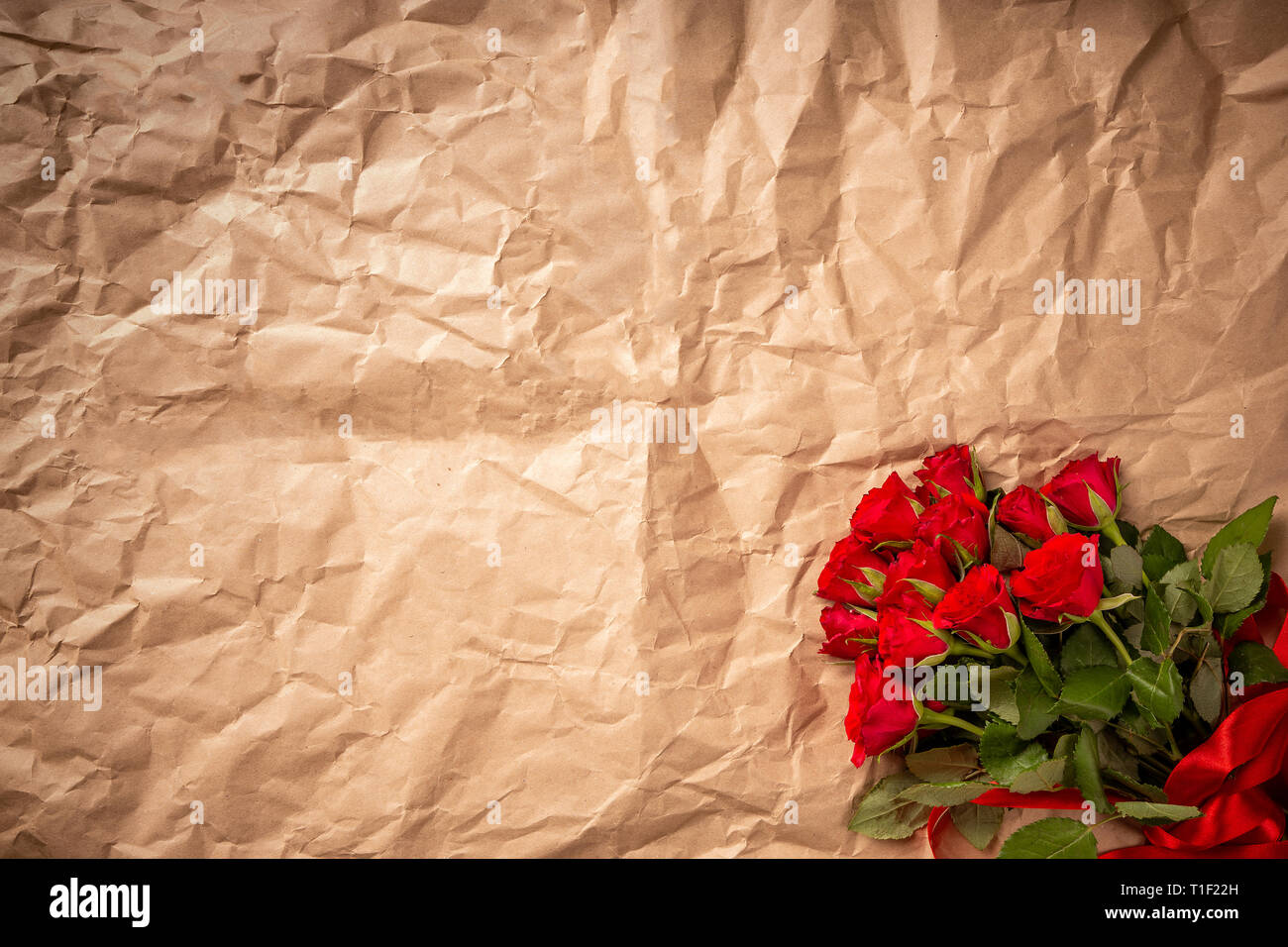 Blumenstrauß aus roten Rosen auf gewickelt Papier Hintergrund Stockfoto